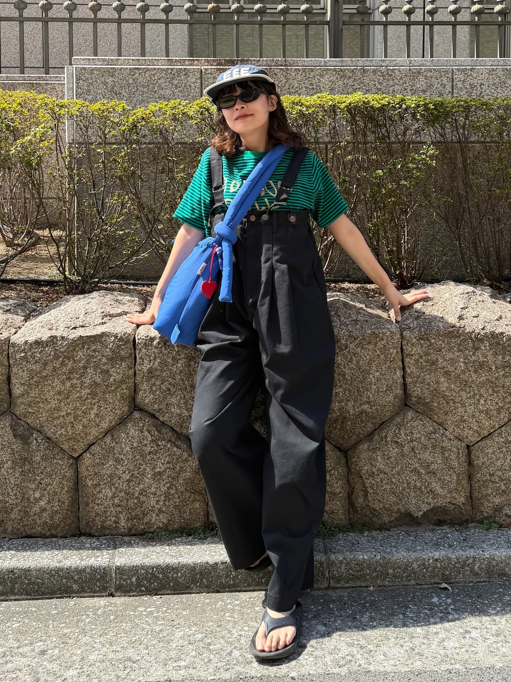 グレー系のTシャツ/カットソー、ベージュ系のチノパンツ、ブルー系のハンドバッグを着用したレディースの夏コーディネートの2枚目の写真
