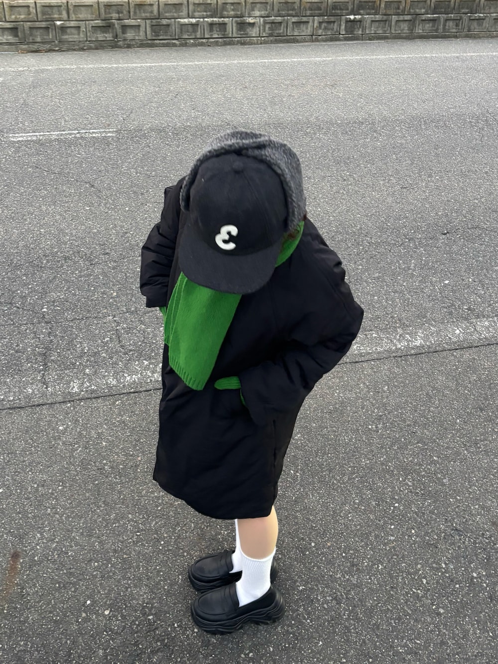 ブラック系のモッズコート、ブラック系のローファー、グレー系のキャップを着用したレディースの冬コーディネートの3枚目の写真