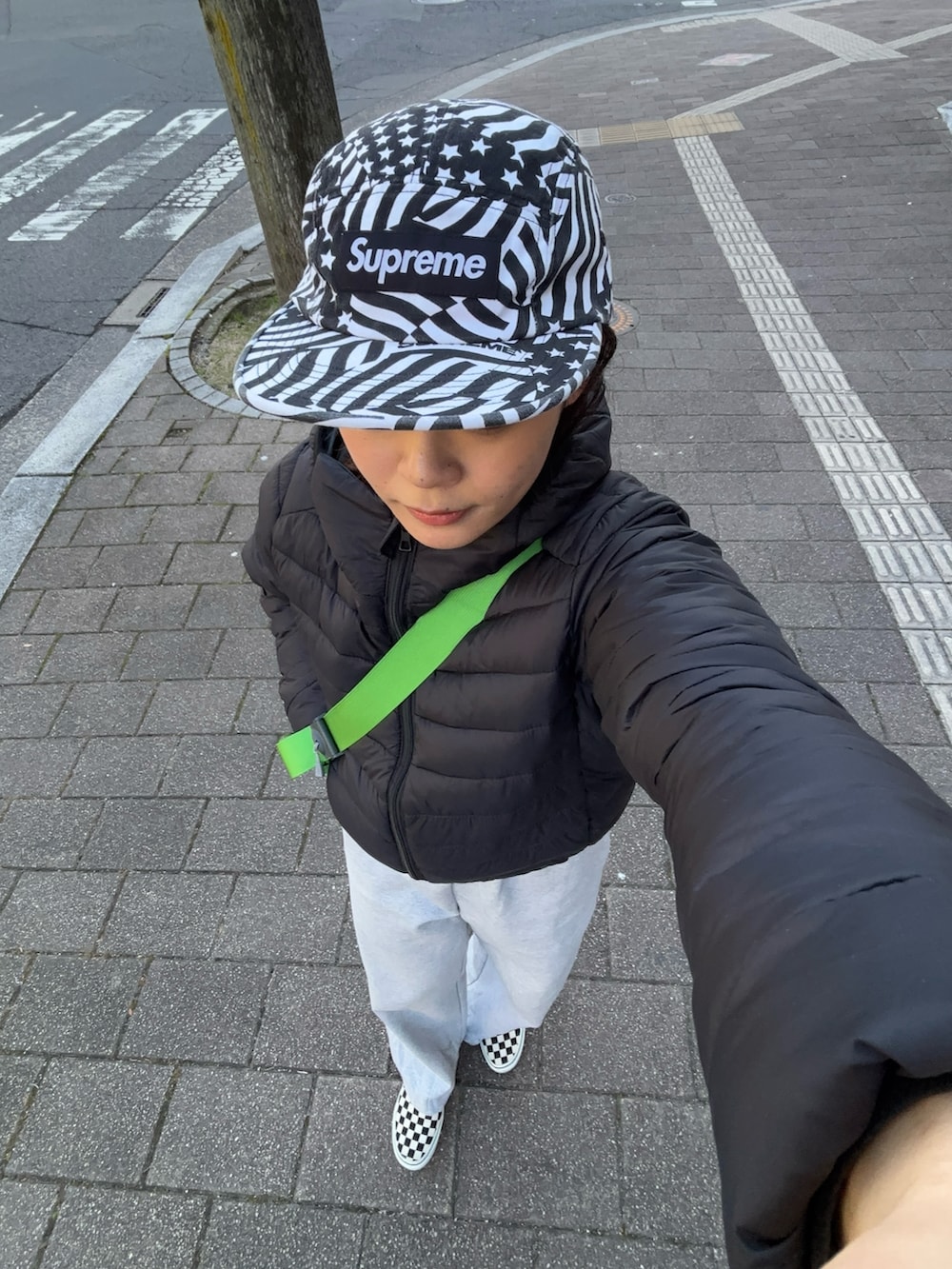 グレー系のスウェットパンツ、ホワイト系のスリッポン、グリーン系のショルダーバッグを着用したレディースの冬コーディネートの3枚目の写真