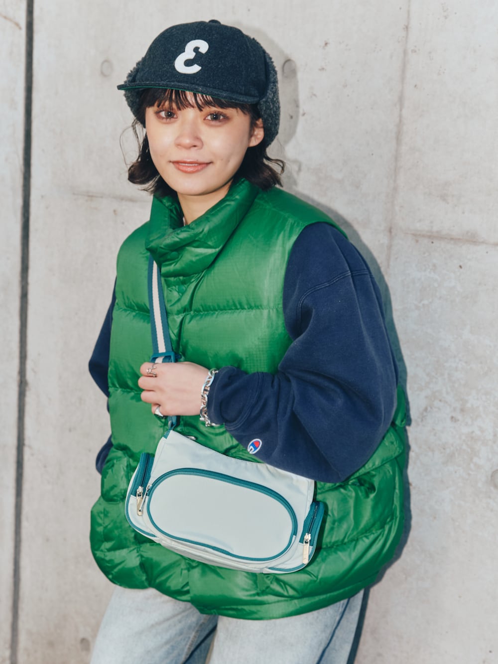 グリーン系のダウンベスト、ブルー系のバッグ、ブルー系のデニムパンツを着用したレディースの春コーディネートの2枚目の写真