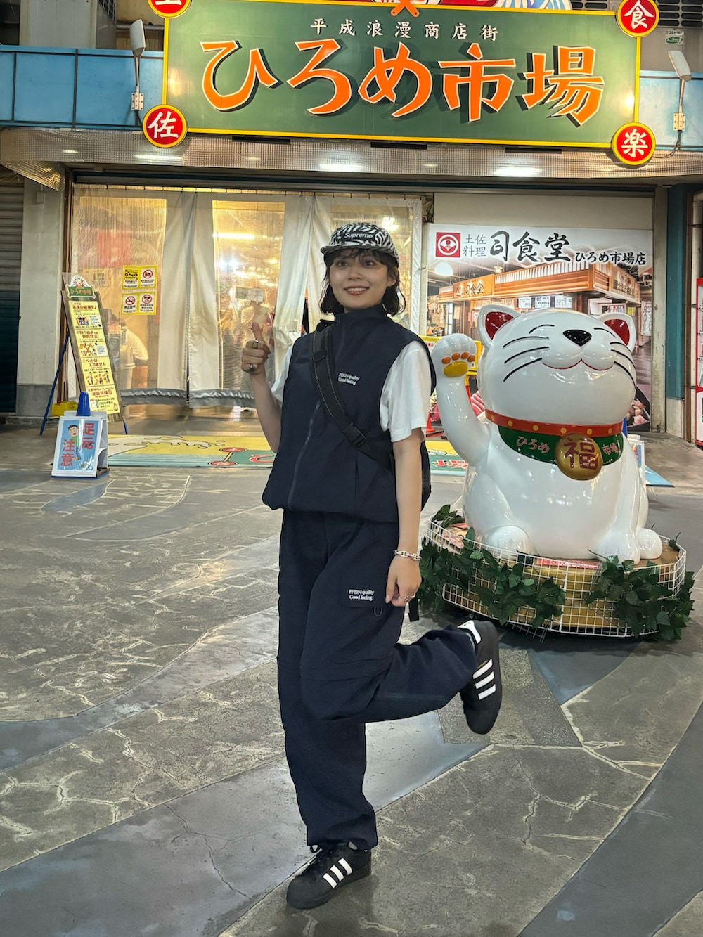 ブラック系のスニーカー、ブルー系のベスト、ブルー系のパンツを着用したレディースの夏コーディネートの2枚目の写真