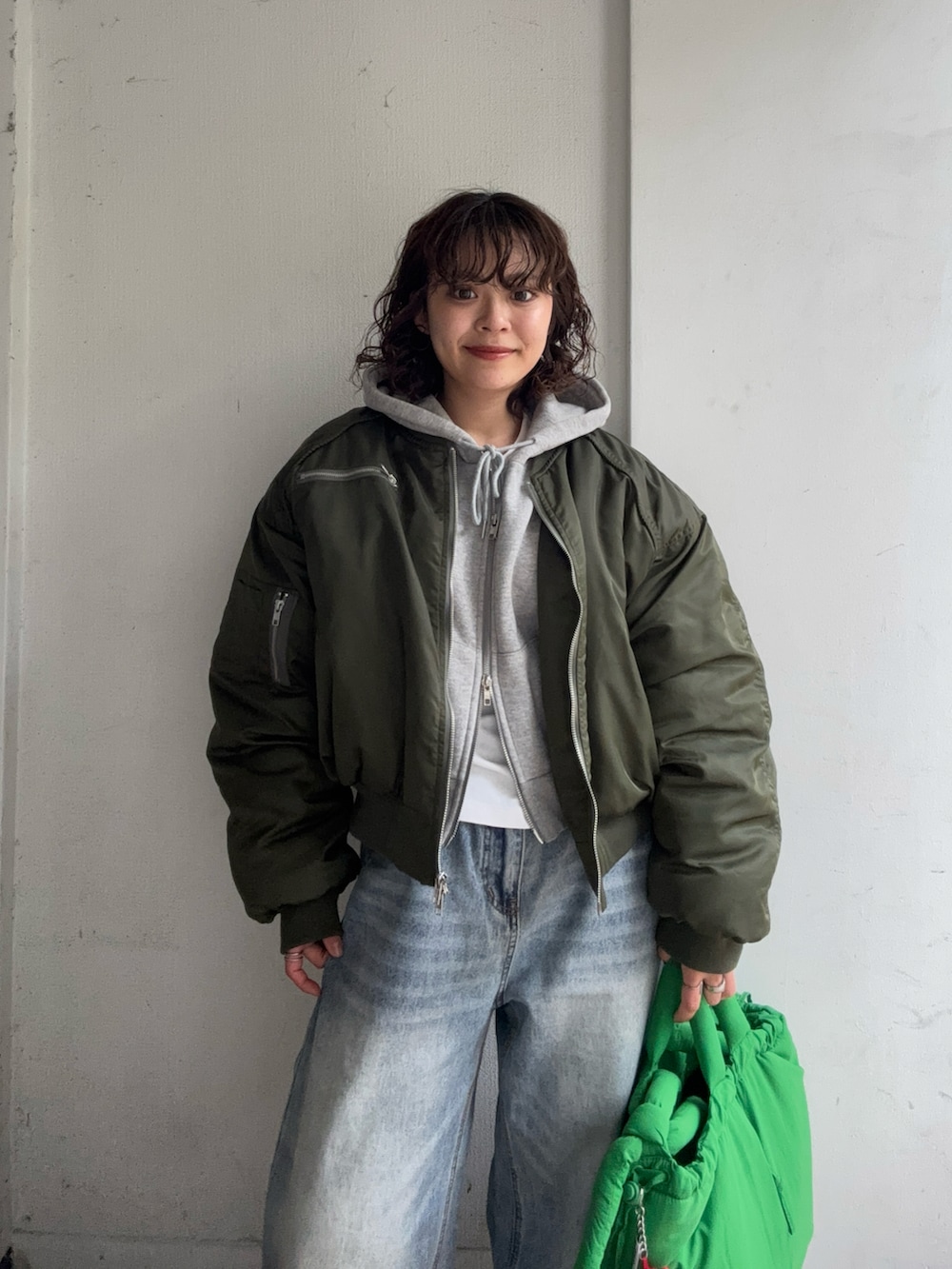グリーン系のMA-1、グレー系のトップス、ホワイト系のTシャツ/カットソーを着用したレディースの春コーディネートの3枚目の写真