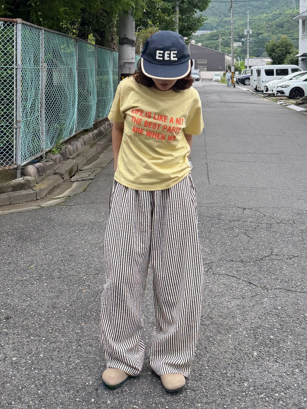 イエロー系のTシャツ/カットソー、ベージュ系のサンダル、ホワイト系のパンツを着用したレディースの夏コーディネートの2枚目の写真