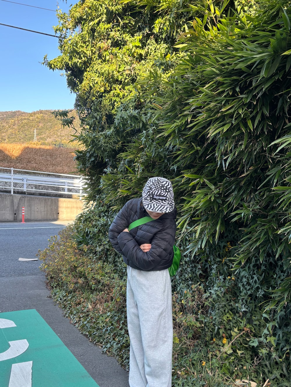 グレー系のスウェットパンツ、ホワイト系のスリッポン、グリーン系のショルダーバッグを着用したレディースの冬コーディネートの2枚目の写真