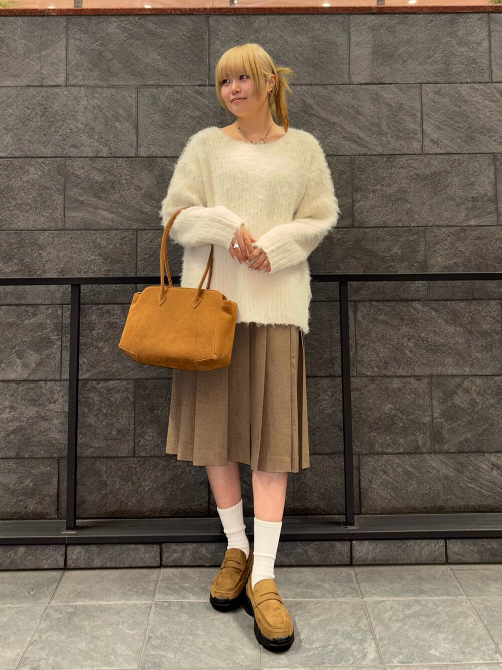 ホワイト系のニット/セーター、ブラウン系のスカート、イエロー系のボストンバッグを着用したレディースの冬コーディネートの2枚目の写真