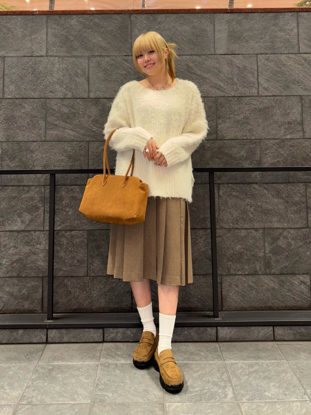ホワイト系のニット/セーター、ブラウン系のスカート、イエロー系のボストンバッグを着用したレディースの冬コーディネートの3枚目の写真