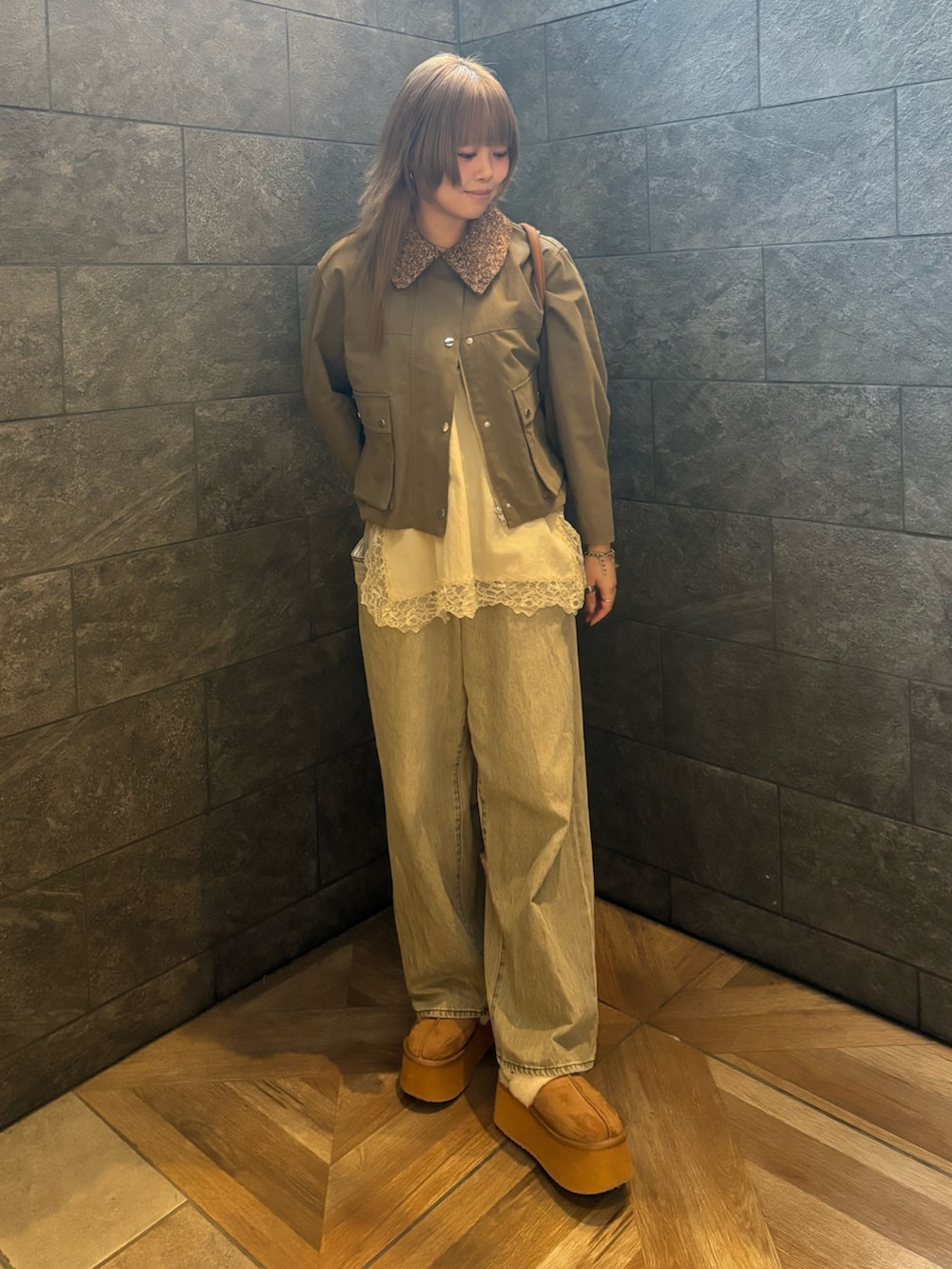 グリーン系のブルゾン、ベージュ系のキャミソール、グリーン系のデニムパンツを着用したレディースの冬コーディネートの4枚目の写真