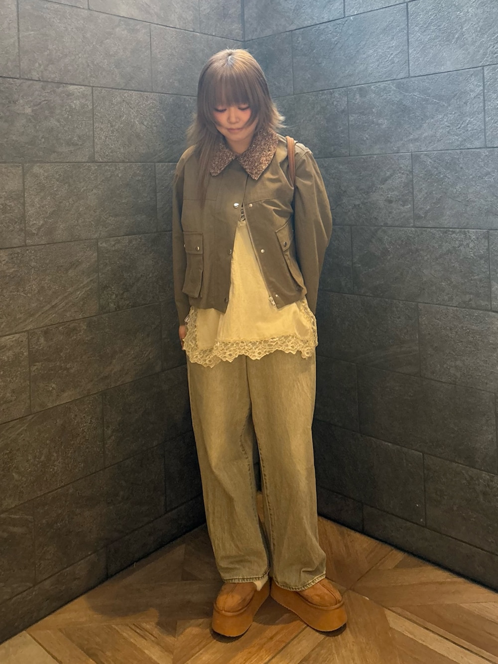 グリーン系のブルゾン、ベージュ系のキャミソール、グリーン系のデニムパンツを着用したレディースの冬コーディネートの3枚目の写真