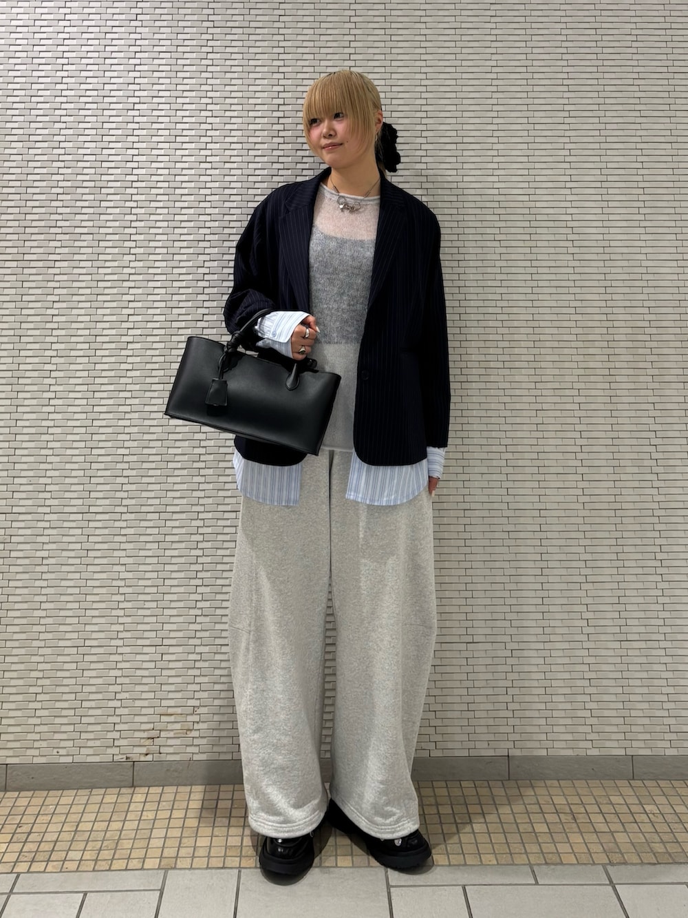 ブルー系のその他アウター、ブルー系のニット/セーター、ブラック系のハンドバッグを着用したレディースの春コーディネートの2枚目の写真