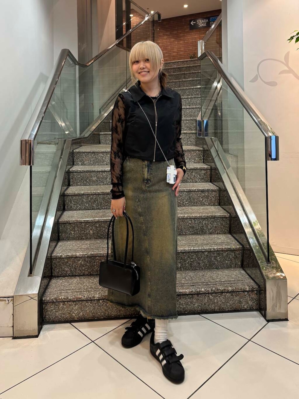 ブラック系のベスト、ブルー系のスカート、ブラック系のTシャツ/カットソーを着用したレディースの春コーディネートの2枚目の写真