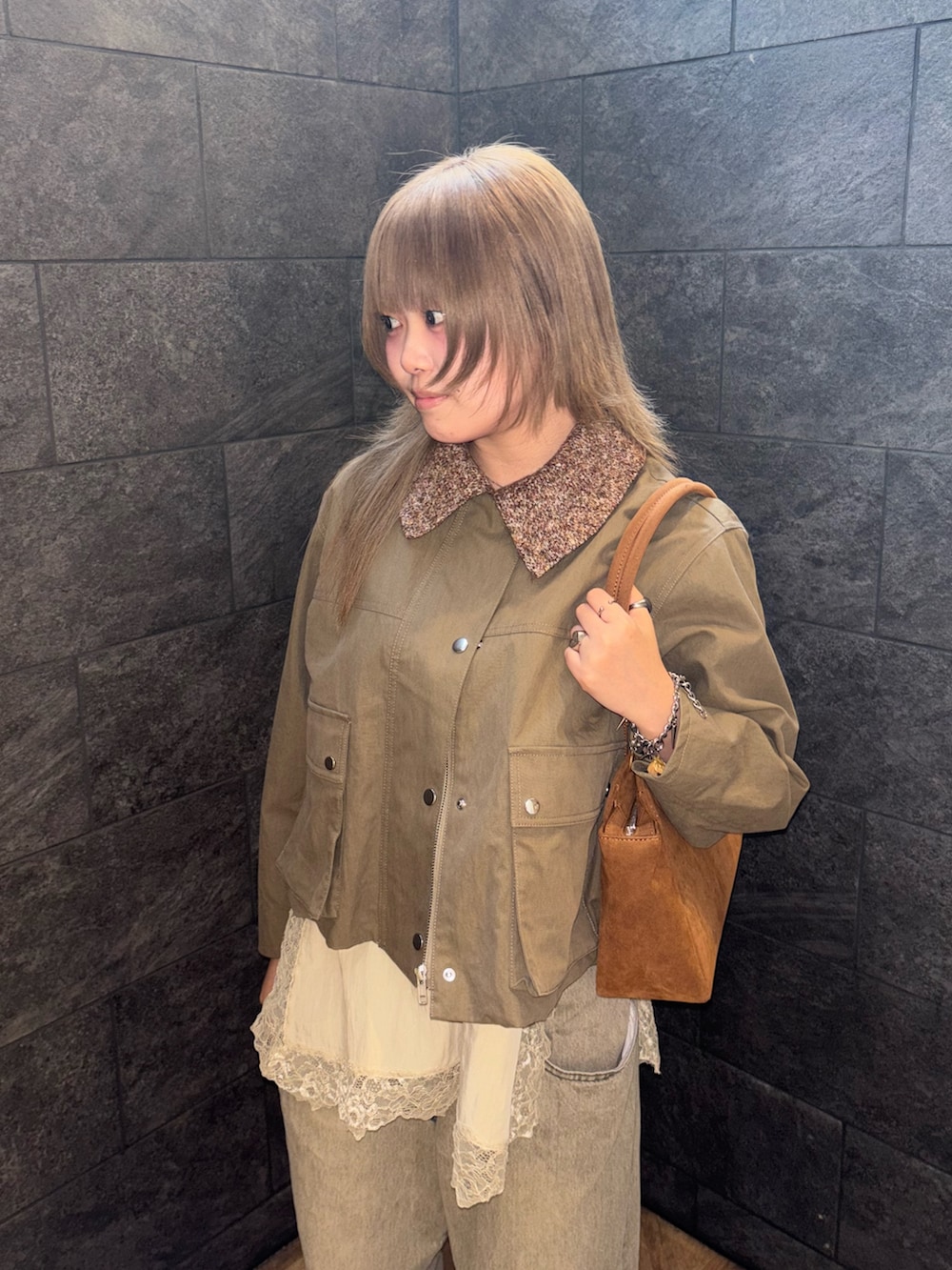 グリーン系のブルゾン、ベージュ系のキャミソール、グリーン系のデニムパンツを着用したレディースの冬コーディネートの2枚目の写真