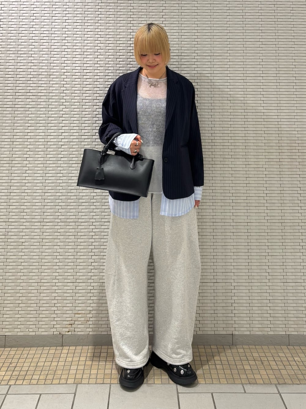 ブルー系のその他アウター、ブルー系のニット/セーター、ブラック系のハンドバッグを着用したレディースの春コーディネートの4枚目の写真