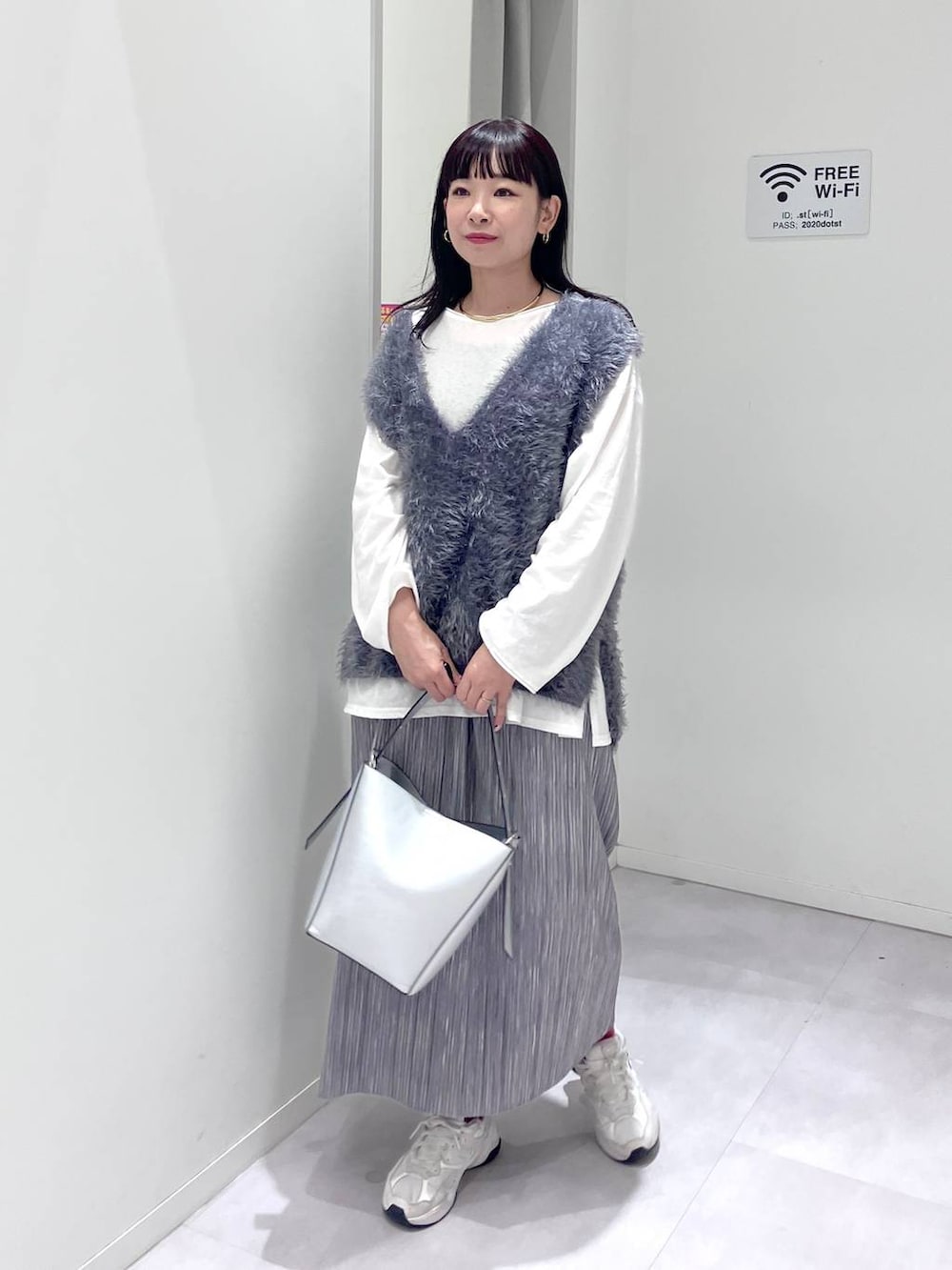 シルバー系のショルダーバッグ、グレー系のスカート、グレー系のベストを着用したレディースの秋コーディネートの3枚目の写真