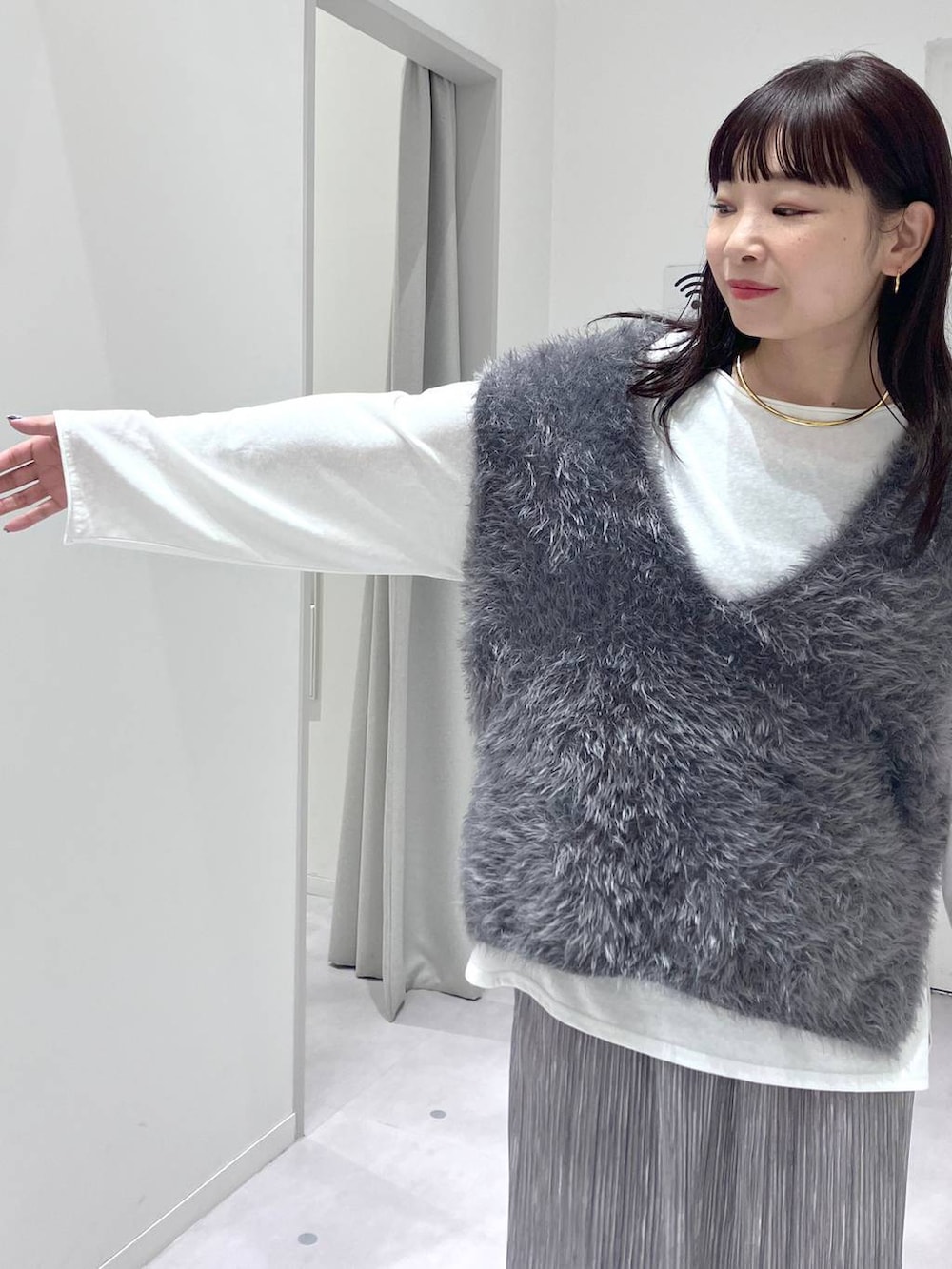 シルバー系のショルダーバッグ、グレー系のスカート、グレー系のベストを着用したレディースの秋コーディネートの7枚目の写真