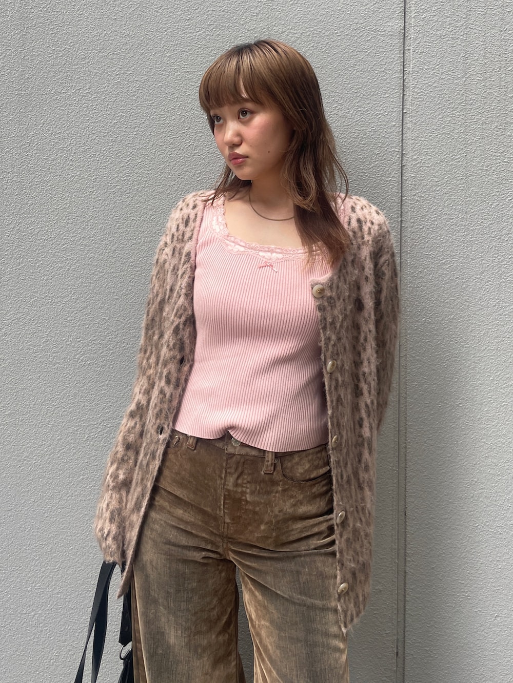 ブラウン系のデニムパンツ、ピンク系のカーディガン/ボレロ、ブラック系のブーツを着用したレディースの秋コーディネートの2枚目の写真