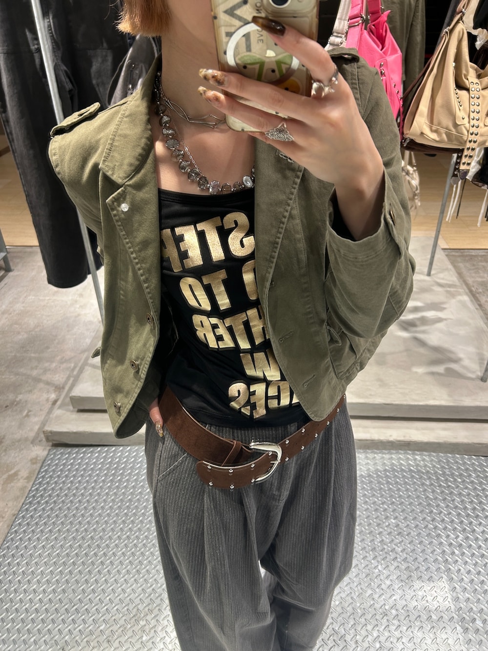 グリーン系のミリタリージャケット、ブラック系のTシャツ/カットソー、グレー系のその他パンツを着用したレディースの秋コーディネートの2枚目の写真