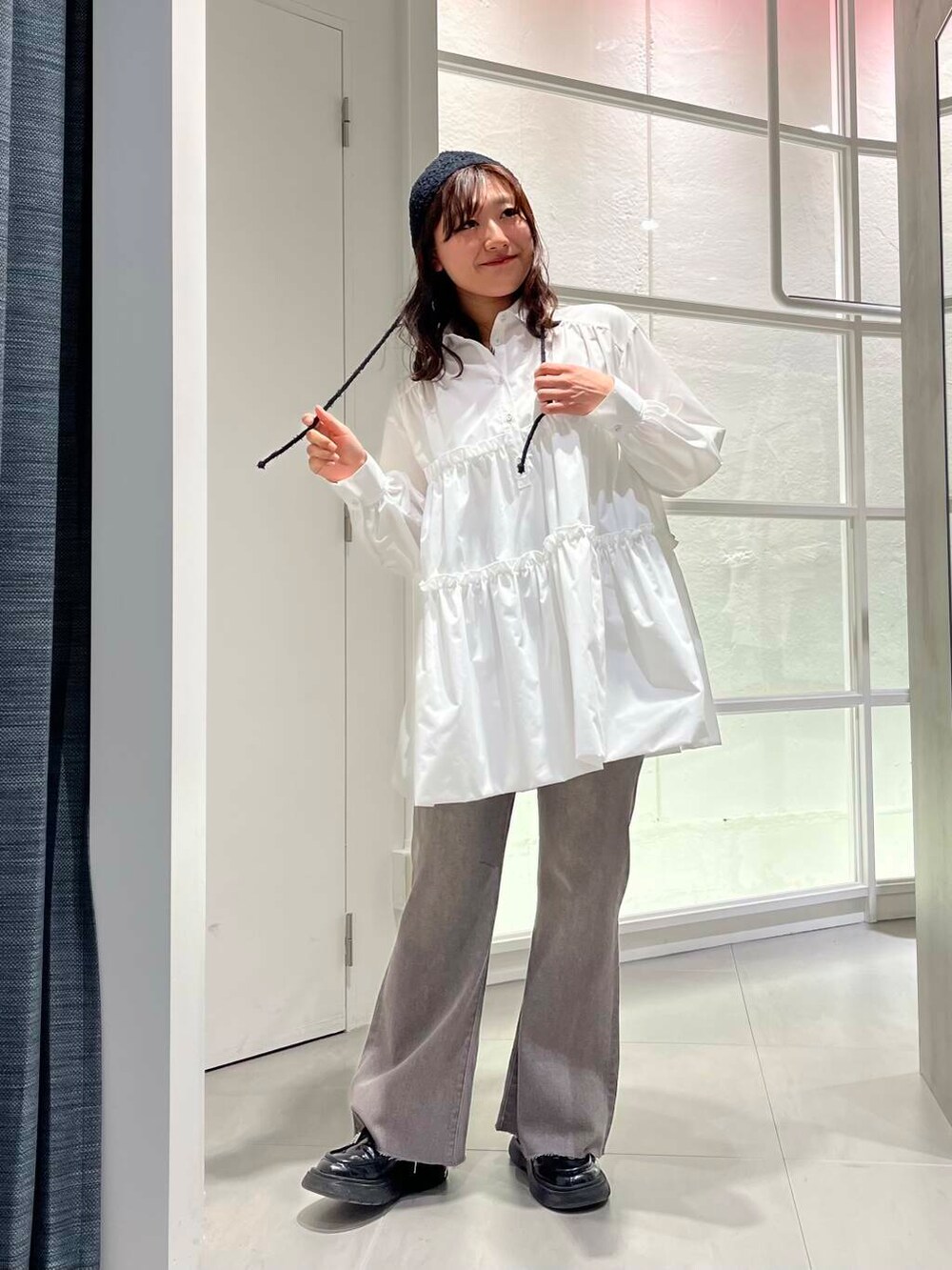 ブラック系のローファー、ホワイト系のワンピース、グレー系のデニムパンツを着用したレディースの冬コーディネートの2枚目の写真