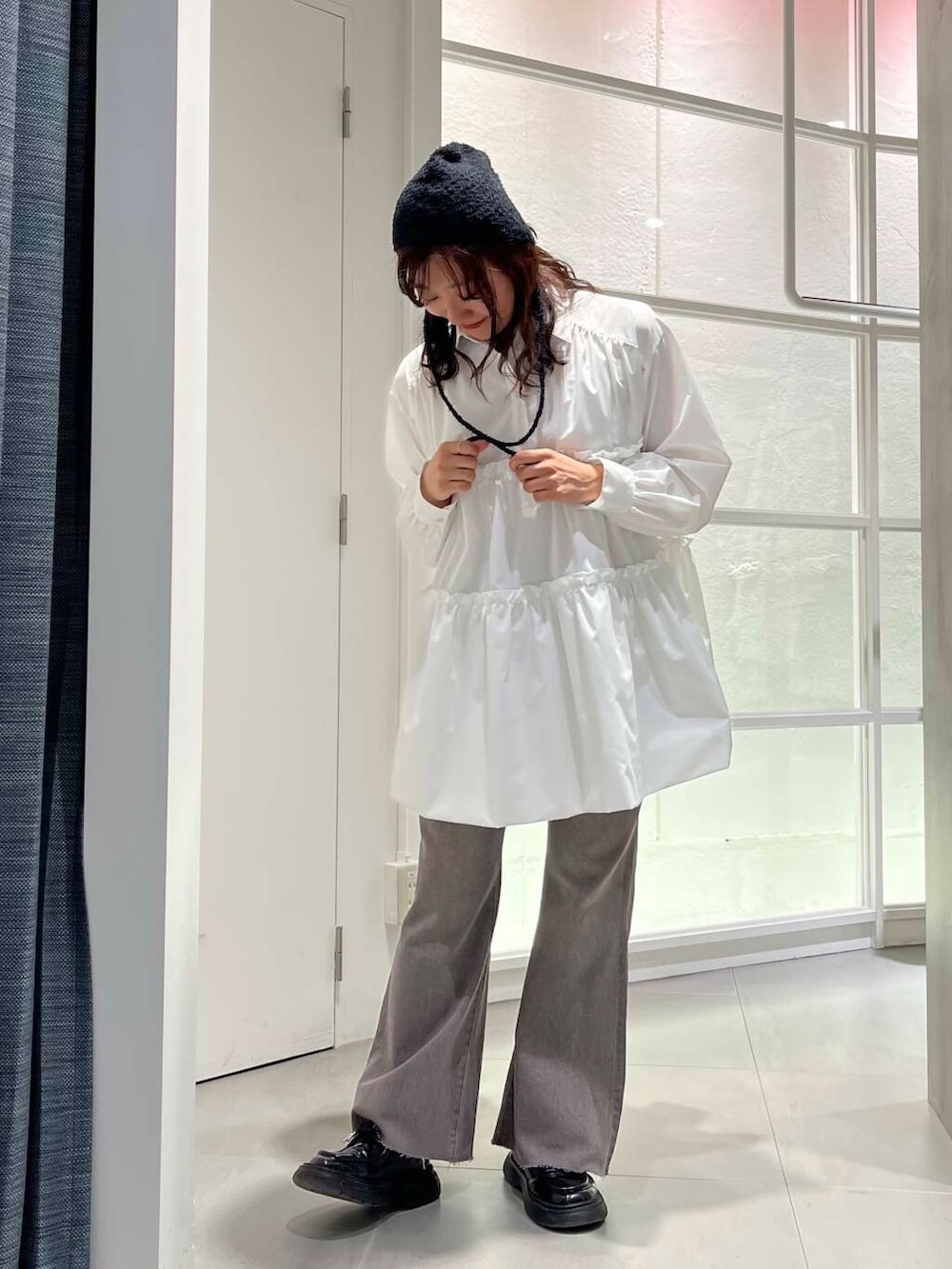 ブラック系のローファー、ホワイト系のワンピース、グレー系のデニムパンツを着用したレディースの冬コーディネートの3枚目の写真