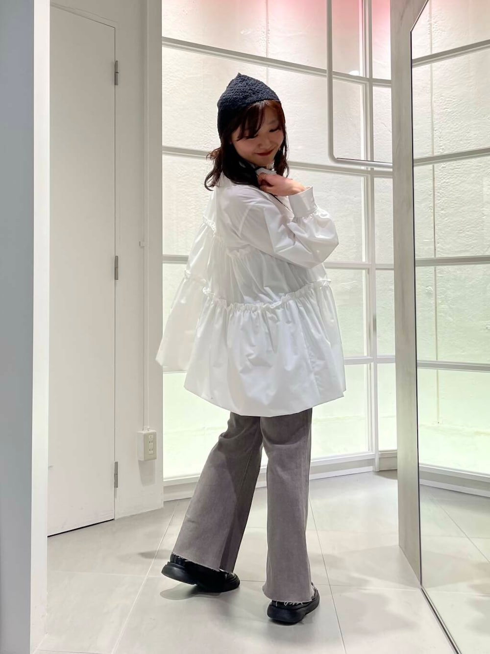 ブラック系のローファー、ホワイト系のワンピース、グレー系のデニムパンツを着用したレディースの冬コーディネートの6枚目の写真