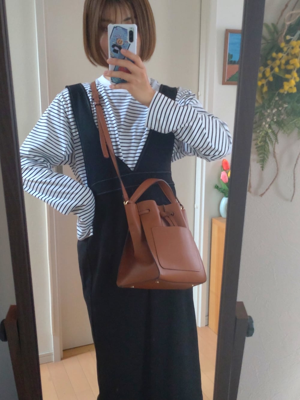 ブラウン系のショルダーバッグ、ブラック系のオールインワン・サロペット、ブラック系のドレスシューズを着用したレディースの春コーディネートの2枚目の写真