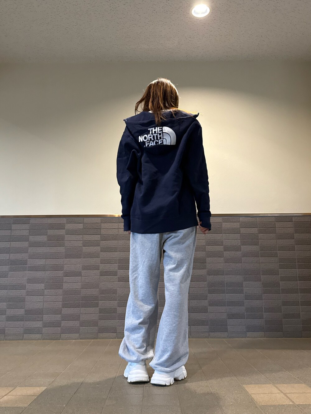 グレー系のスウェットパンツ、ブルー系のパーカー、ホワイト系のスニーカーを着用したレディースの春コーディネートの2枚目の写真