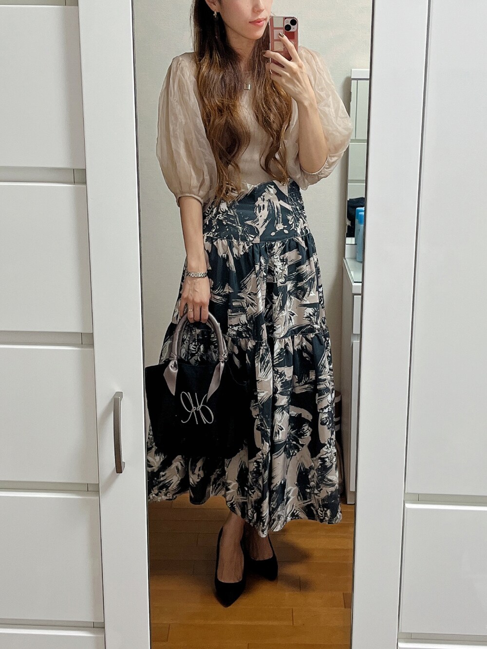 ベージュ系のニット/セーター、ベージュ系のスカート、ブラック系のトートバッグを着用したレディースの秋コーディネートの2枚目の写真