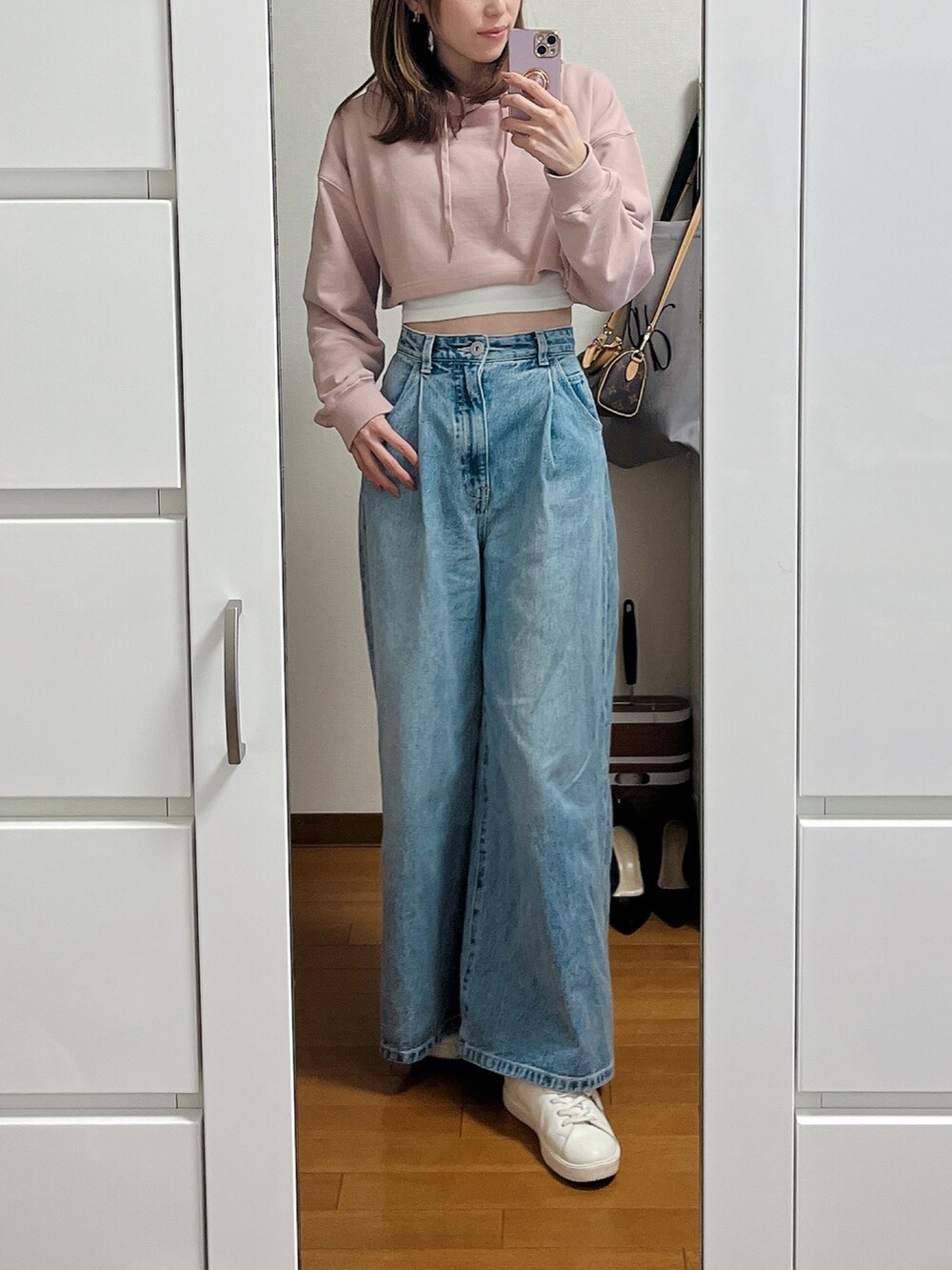 ピンク系のスウェット、ブルー系のデニムパンツ、ホワイト系のスニーカーを着用したレディースの春コーディネートの2枚目の写真