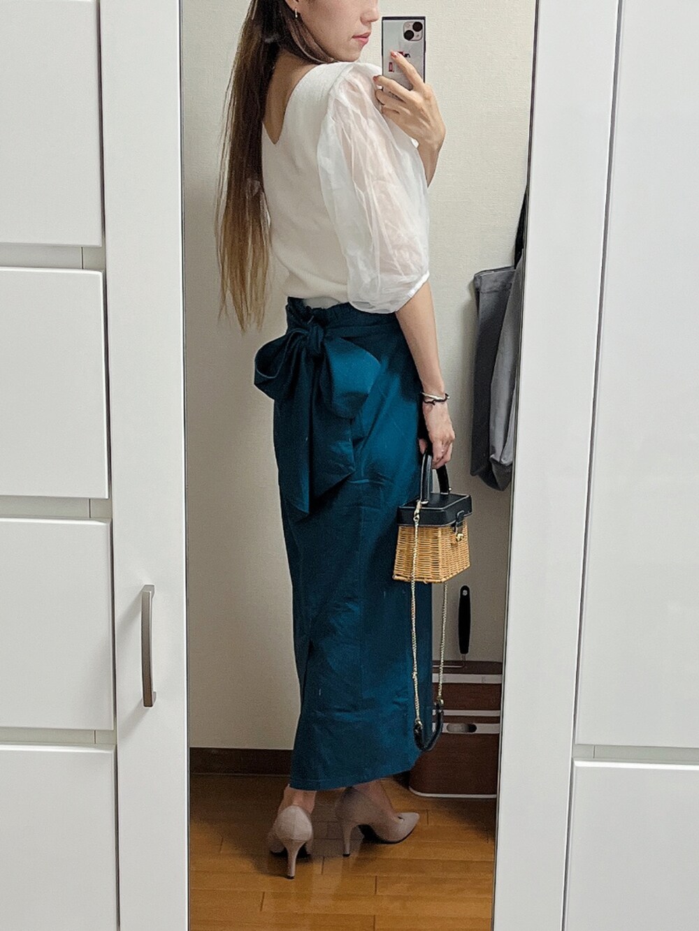 ホワイト系のニット/セーター、ブルー系のスカート、ベージュ系のショルダーバッグを着用したレディースの夏コーディネートの2枚目の写真