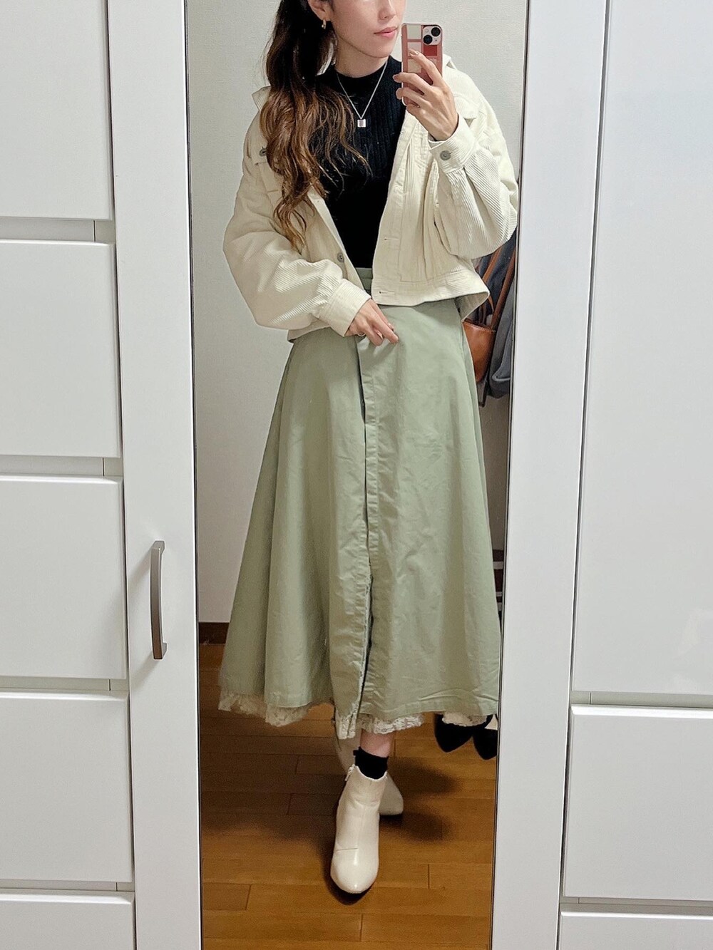 ブラック系のニット/セーター、ブラック系のショルダーバッグ、グリーン系のスカートを着用したレディースの秋コーディネートの2枚目の写真