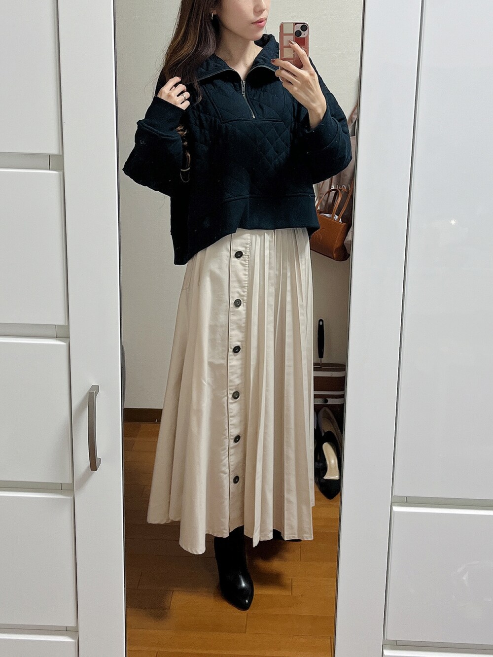 ブラック系のスウェット、ベージュ系のデニムスカート、ブラック系のブーツを着用したレディースの秋コーディネートの2枚目の写真