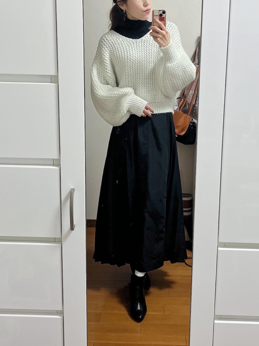 ホワイト系のニット/セーター、グレー系のトートバッグ、ブラック系のスカートを着用したレディースの冬コーディネートの2枚目の写真