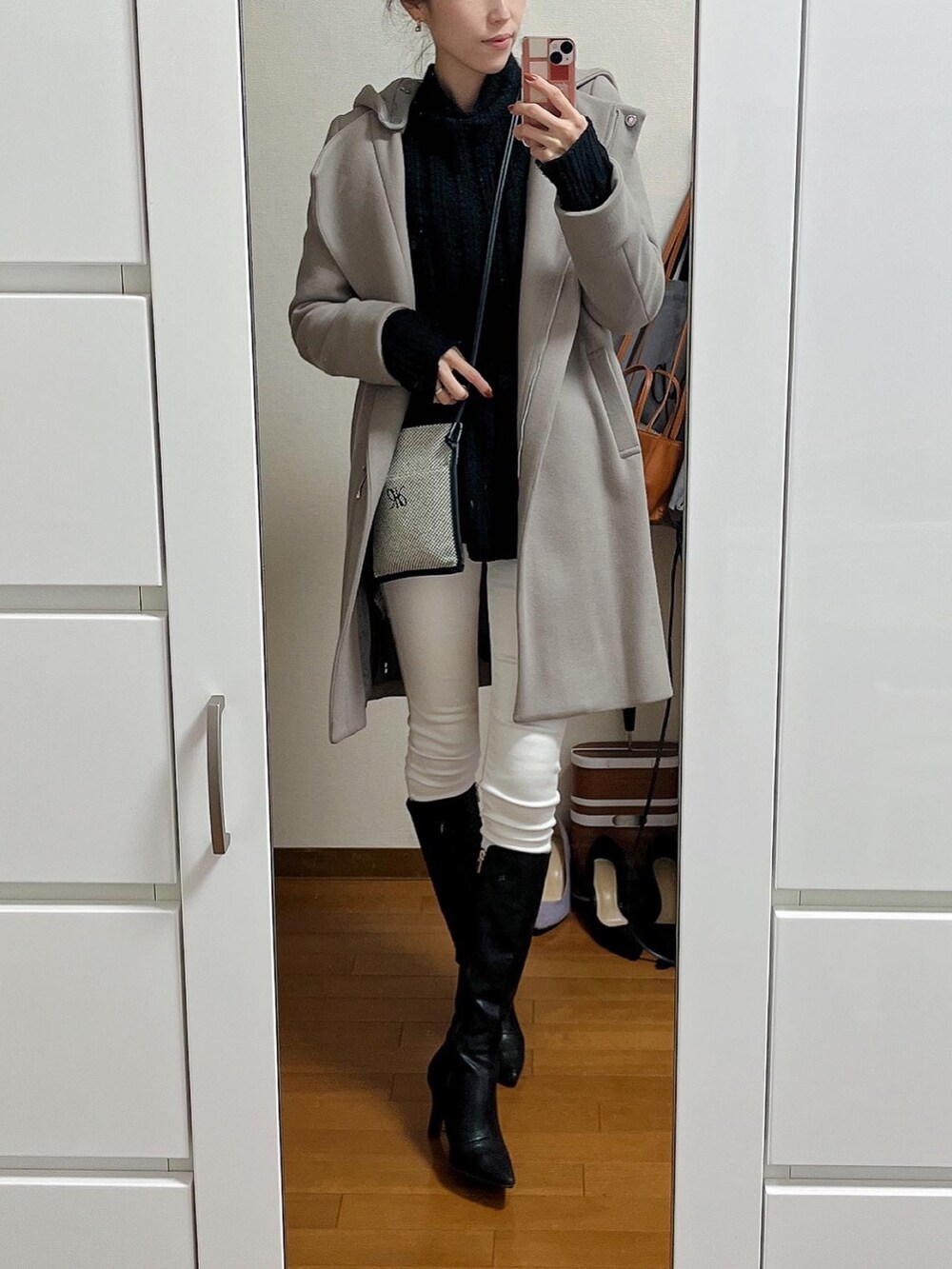 ブラック系のニット/セーター、ホワイト系のデニムパンツ、ブラック系のブーツを着用したレディースの秋コーディネートの2枚目の写真