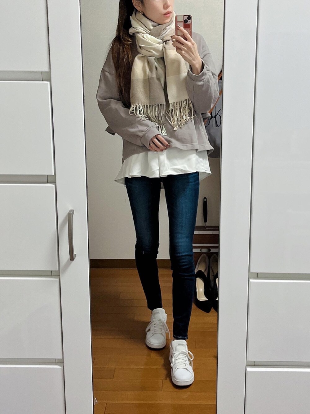 ブラウン系のパーカー、ブルー系のデニムパンツ、ホワイト系のスニーカーを着用したレディースの冬コーディネートの2枚目の写真