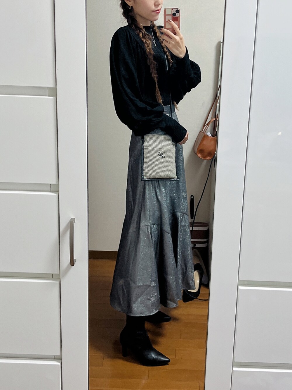 ブラック系のニット/セーター、ブラック系のショルダーバッグ、シルバー系のスカートを着用したレディースの秋コーディネートの2枚目の写真