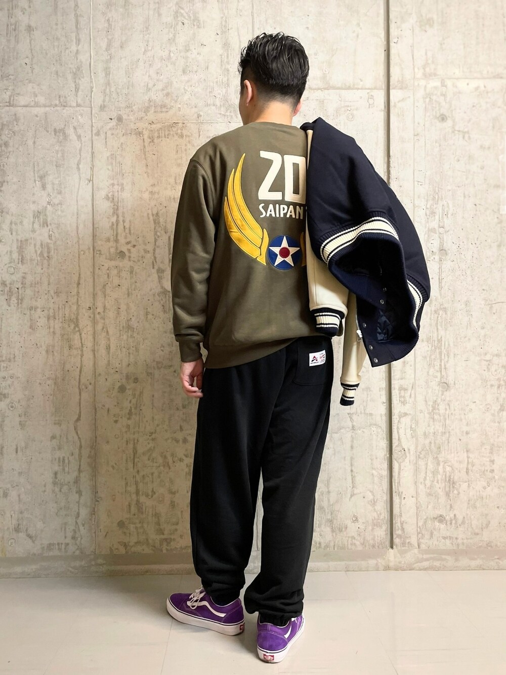 グリーン系のスウェット、ブラック系のスウェットパンツ、ブルー系のスタジャンを着用したメンズの夏コーディネートの2枚目の写真