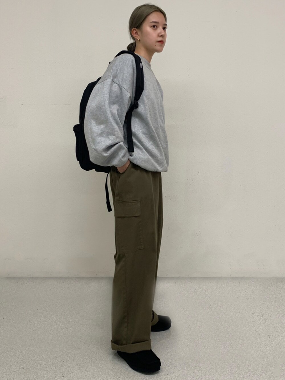 グリーン系のカーゴパンツ、ブラック系のブーツ、ブラック系のバックパック/リュックを着用したレディースの秋コーディネートの2枚目の写真