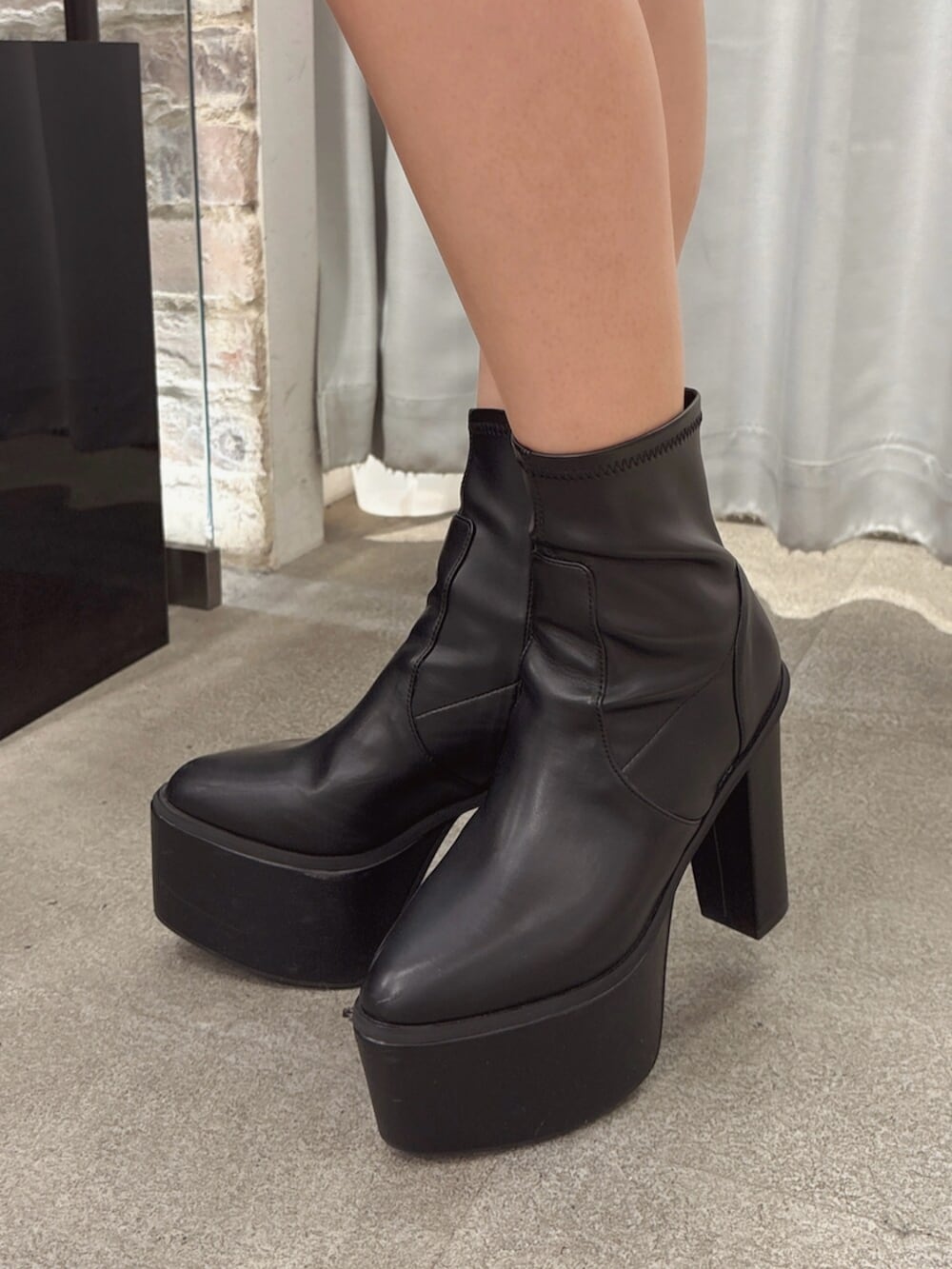 ブラック系のブーツ、ブラック系のワンピース、ホワイト系のベストを着用したレディースの秋コーディネートの5枚目の写真