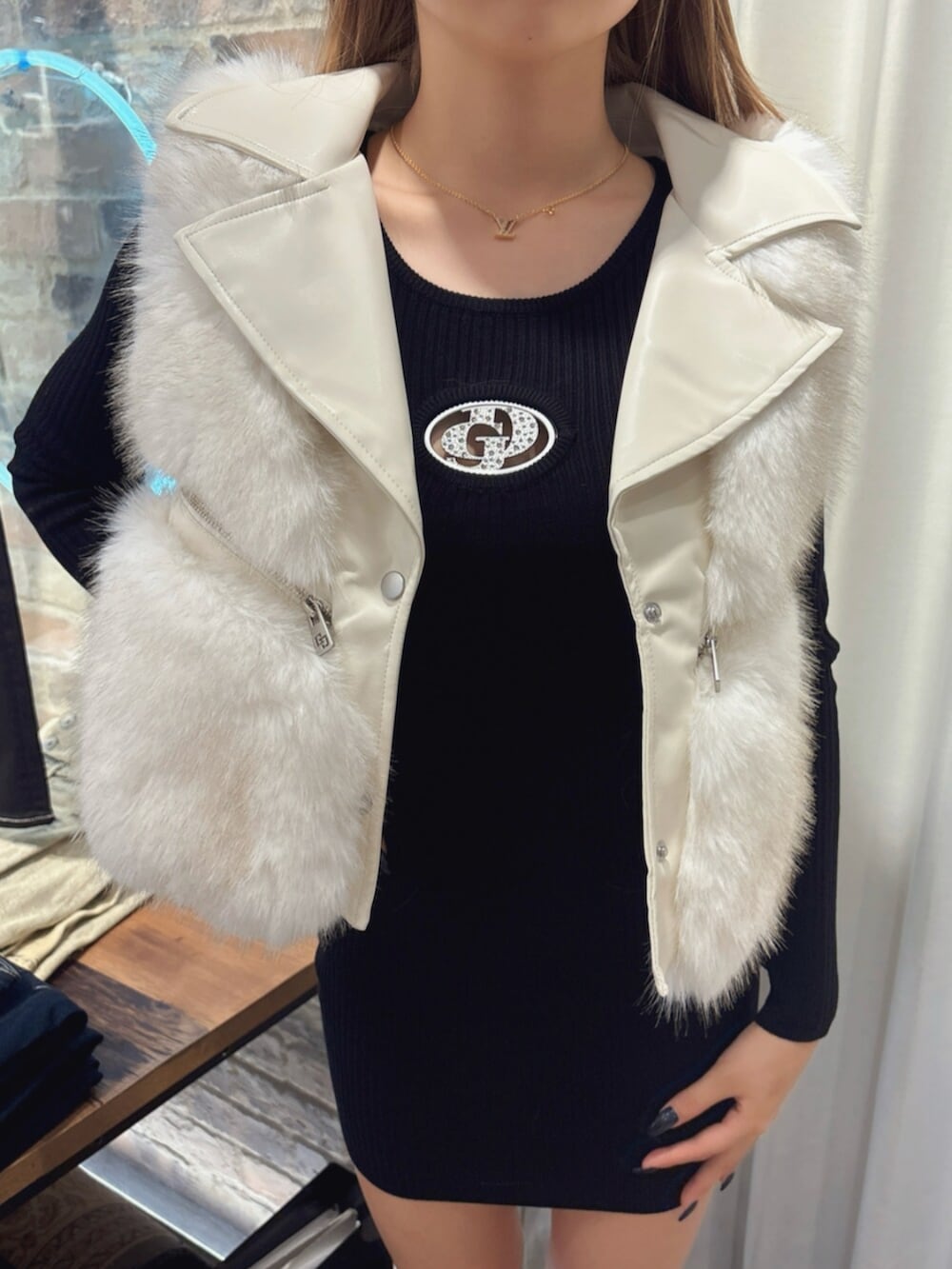 ブラック系のブーツ、ブラック系のワンピース、ホワイト系のベストを着用したレディースの秋コーディネートの4枚目の写真