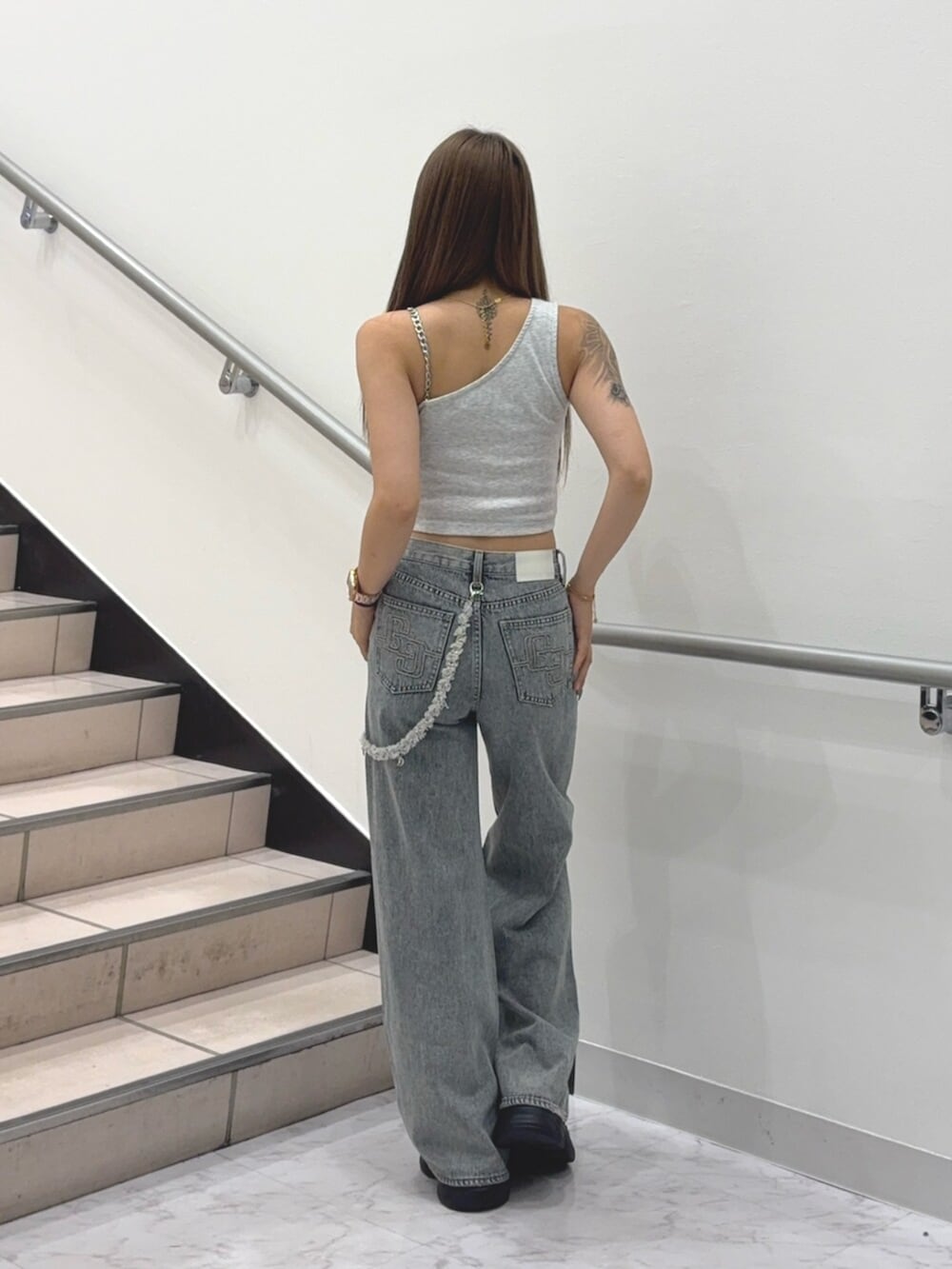 ブラック系のスニーカー、グレー系のタンクトップ、ブルー系のデニムパンツを着用したレディースの夏コーディネートの3枚目の写真