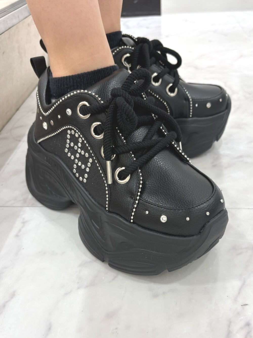 ブラック系のスニーカー、グレー系のタンクトップ、ブルー系のデニムパンツを着用したレディースの夏コーディネートの5枚目の写真
