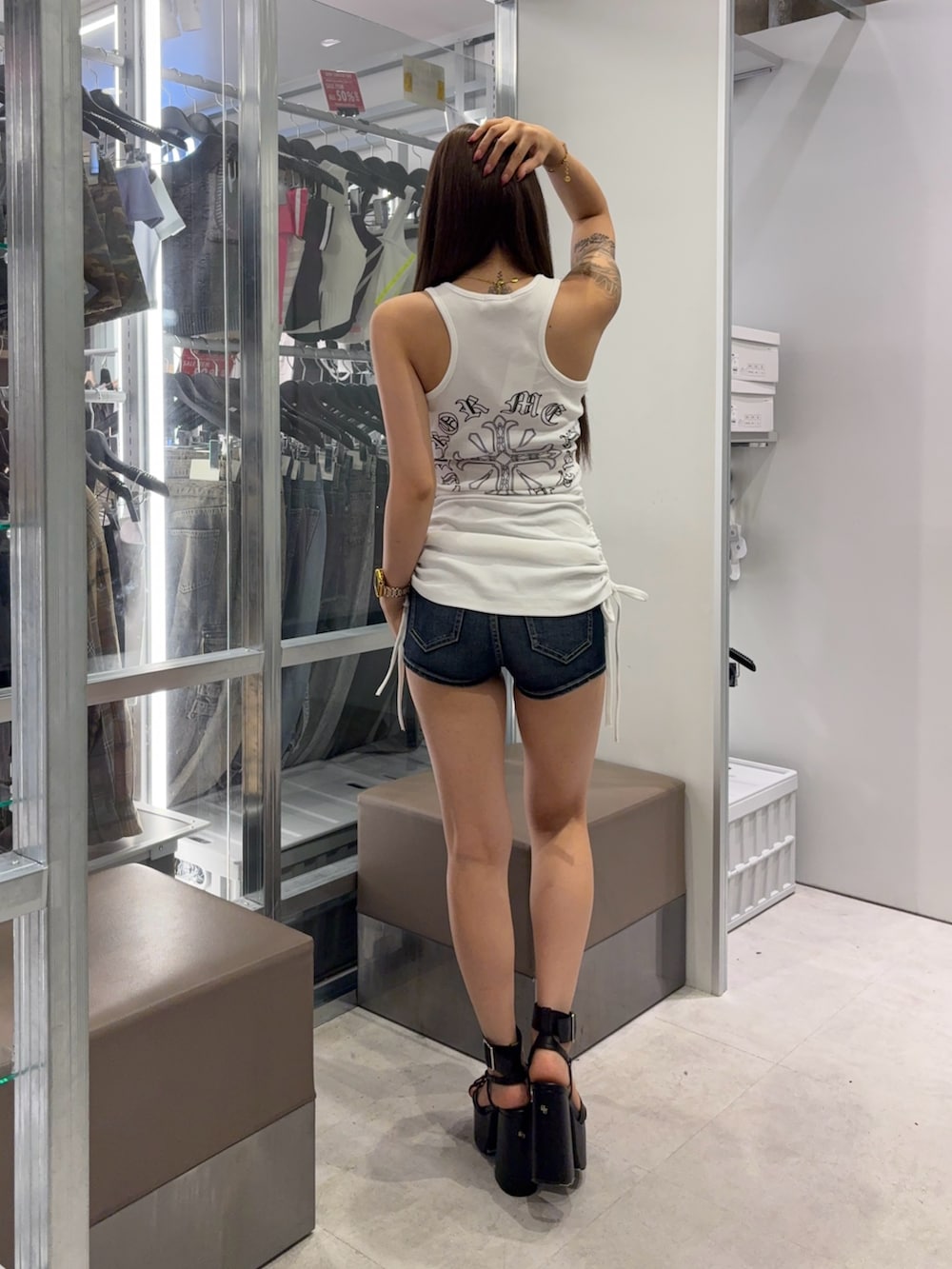 ホワイト系のワンピース、ブルー系のデニムパンツ、ブラック系のサンダルを着用したレディースの夏コーディネートの3枚目の写真