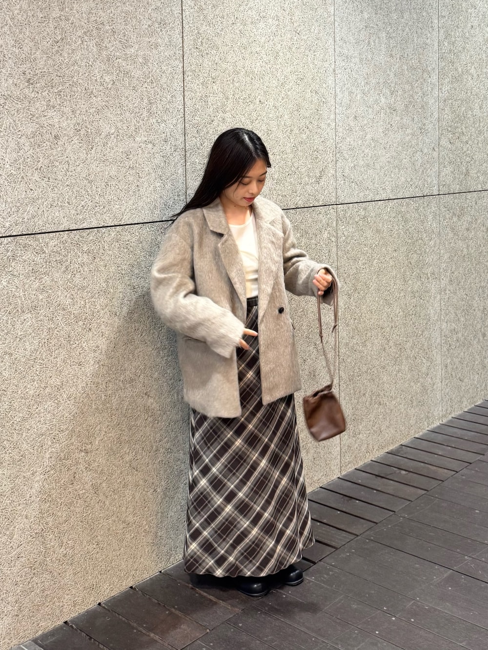 ブラック系のブーツ、ブラウン系のスカート、ブラウン系のショルダーバッグを着用したレディースの秋コーディネートの2枚目の写真