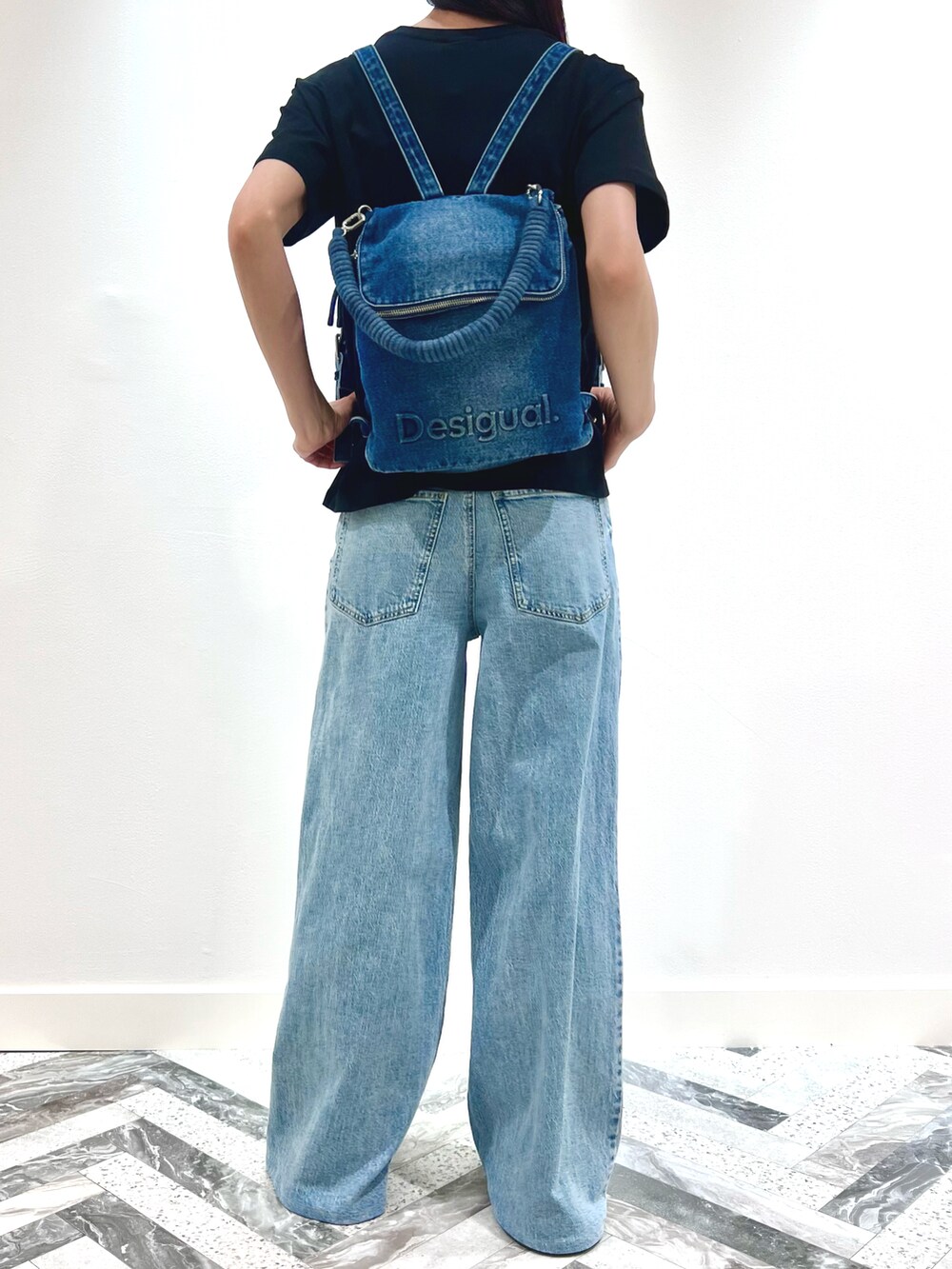 ブラック系のTシャツ/カットソー、ブルー系のデニムパンツ、ブルー系のバックパック/リュックを着用したレディースの春コーディネートの3枚目の写真