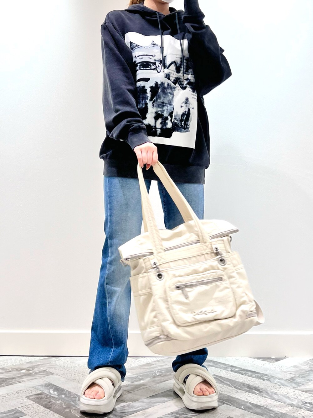 ブラック系のスウェット、ブルー系のデニムパンツ、ホワイト系のバックパック/リュックを着用したレディースの夏コーディネートの2枚目の写真