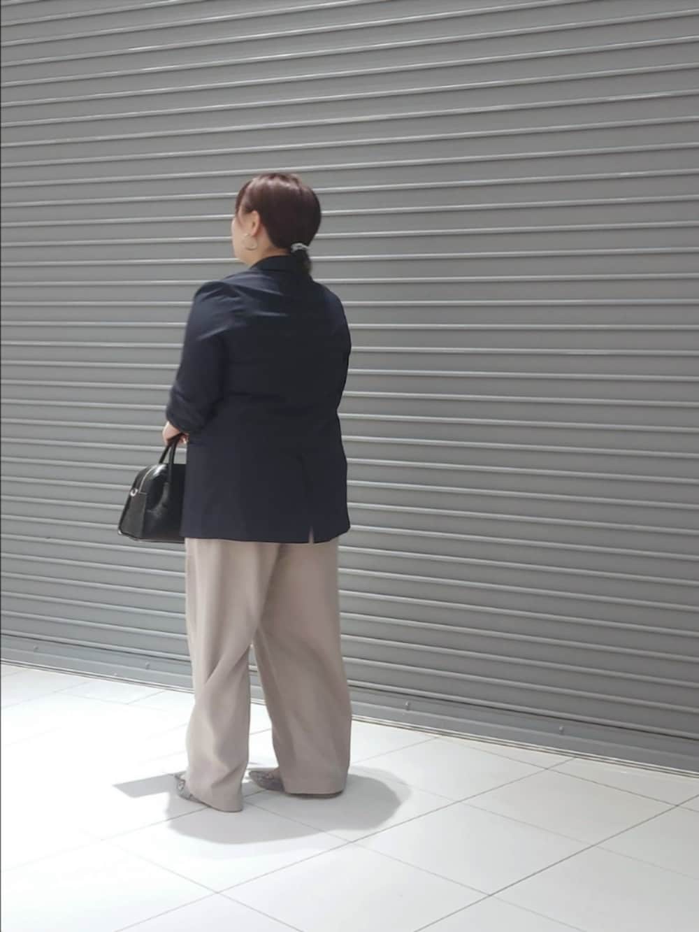 ブルー系のテーラードジャケット、グレー系のその他パンツ、ブラック系のボストンバッグを着用したレディースの夏コーディネートの2枚目の写真