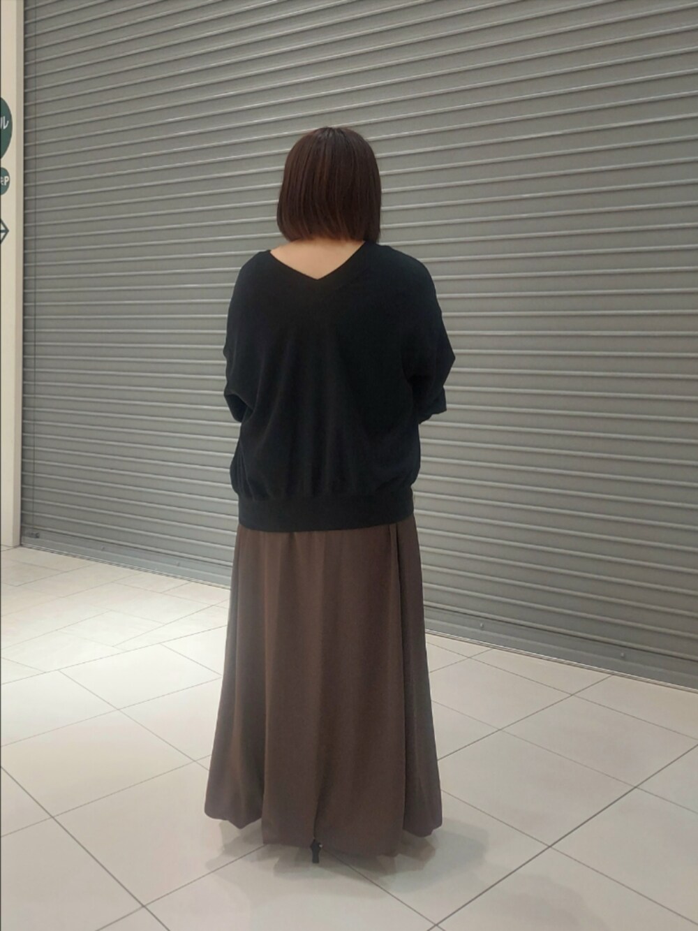 ブラック系のスウェット、ブラウン系のスカート、ブラック系のパンプスを着用したレディースの夏コーディネートの2枚目の写真