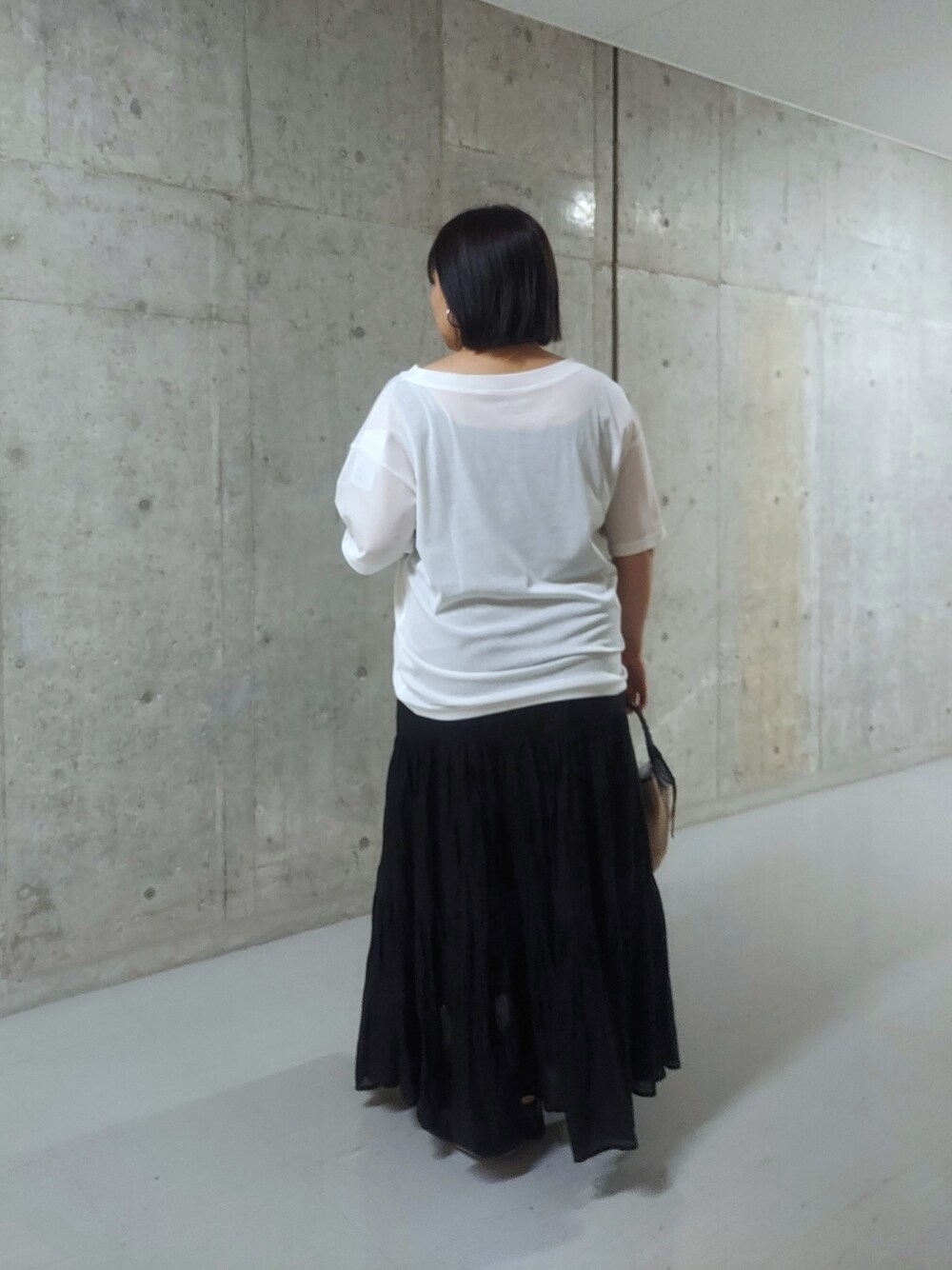 ホワイト系のTシャツ/カットソー、ブラック系のスカート、ブラック系のハンドバッグを着用したレディースの夏コーディネートの2枚目の写真