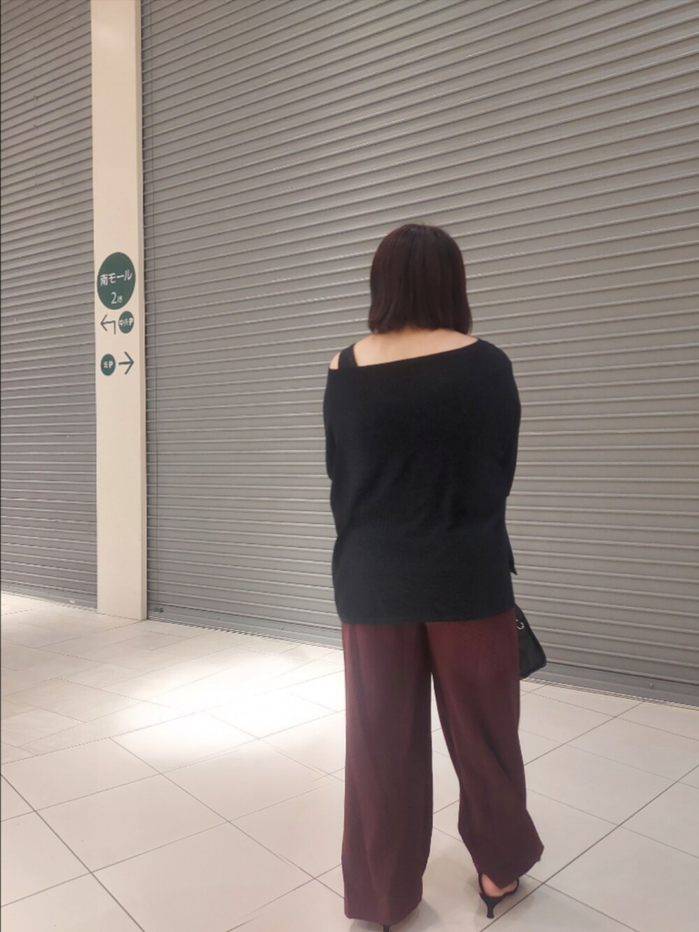 ブラック系のニット/セーター、レッド系のスラックス、ブラック系のパンプスを着用したレディースの夏コーディネートの2枚目の写真