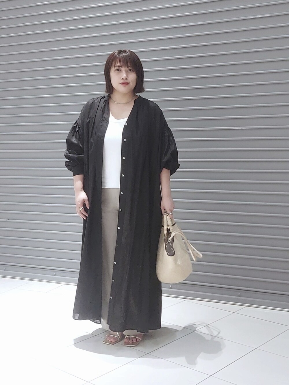 ブラック系のワンピース、ゴールド系のサンダル、ホワイト系のキャミソールを着用したレディースの夏コーディネートの3枚目の写真