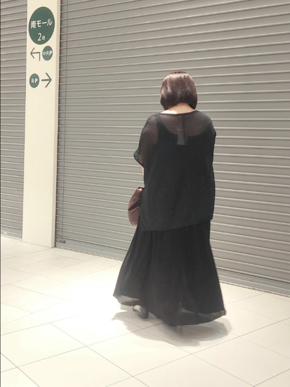 ブラック系のニット/セーター、ブラック系のスカート、ブラウン系のショルダーバッグを着用したレディースの秋コーディネートの2枚目の写真